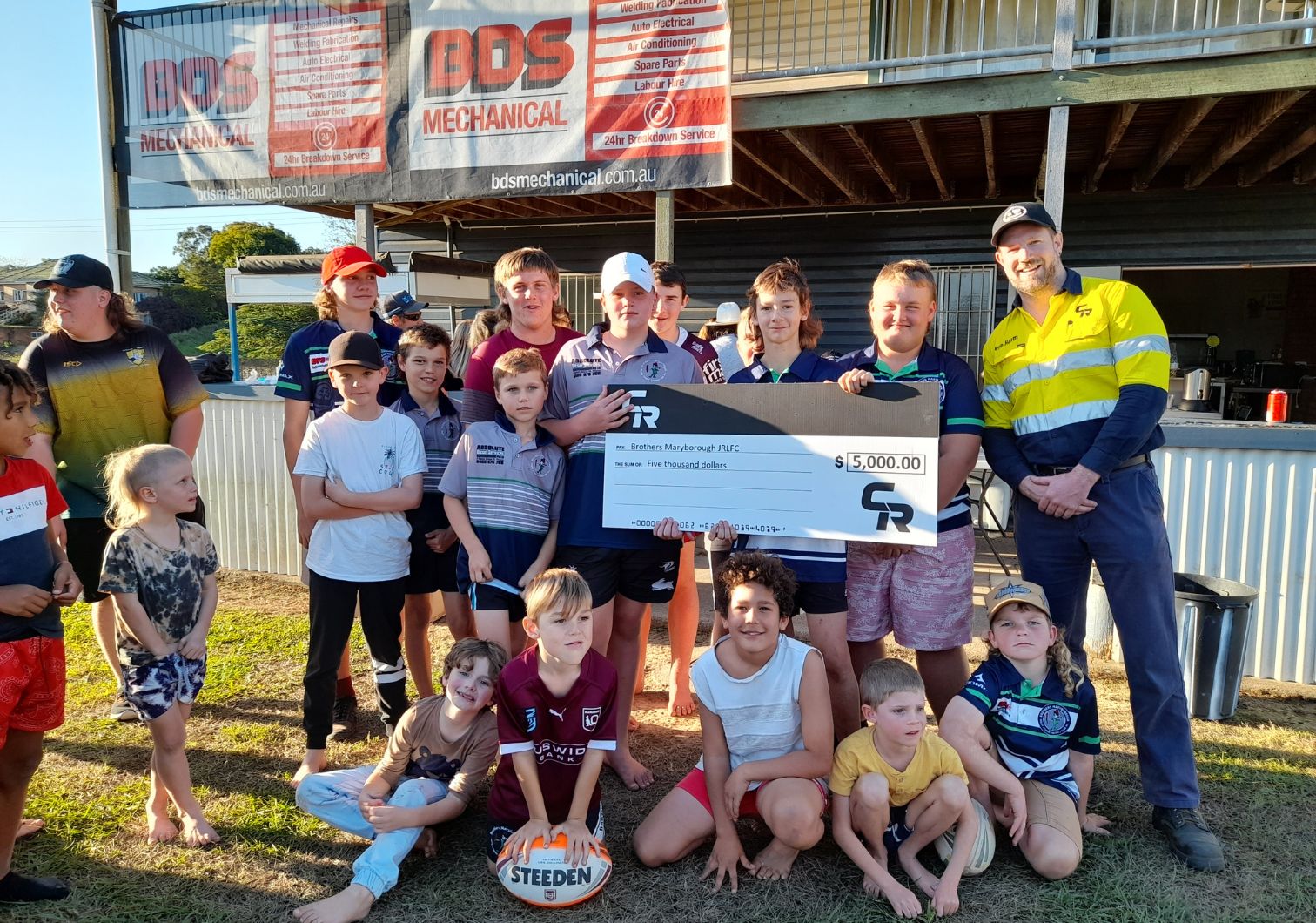 CR presenting a check to Brothers Junior Rugby League in Maryborough after flooding